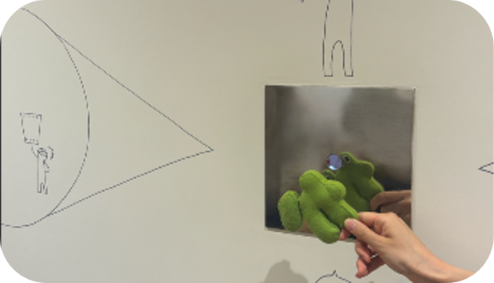 線画が描かれた壁の鏡に、かてぽんを映している様子